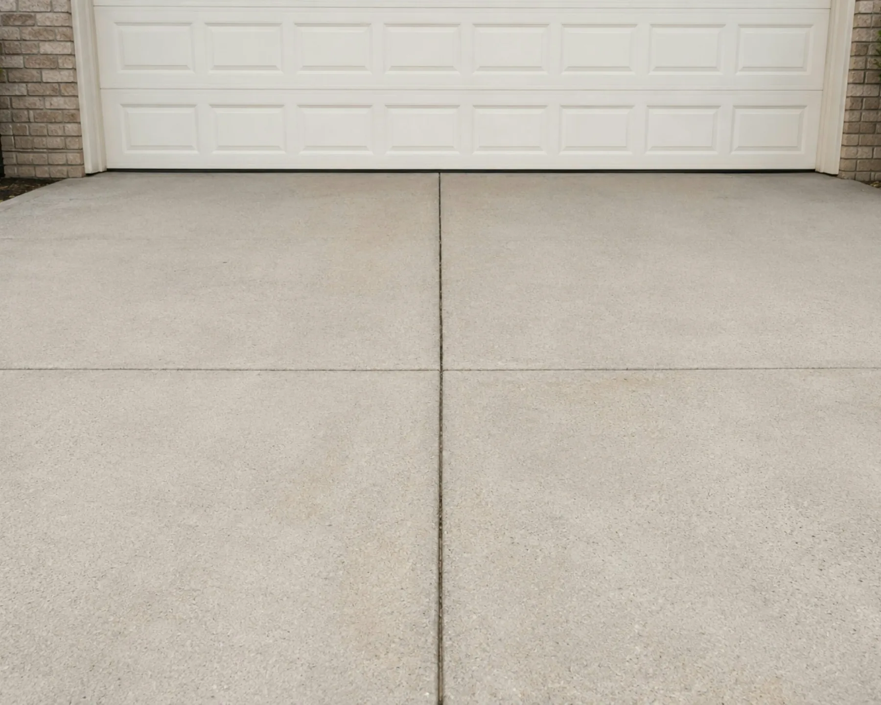 New concrete driveway in front of a white garage door