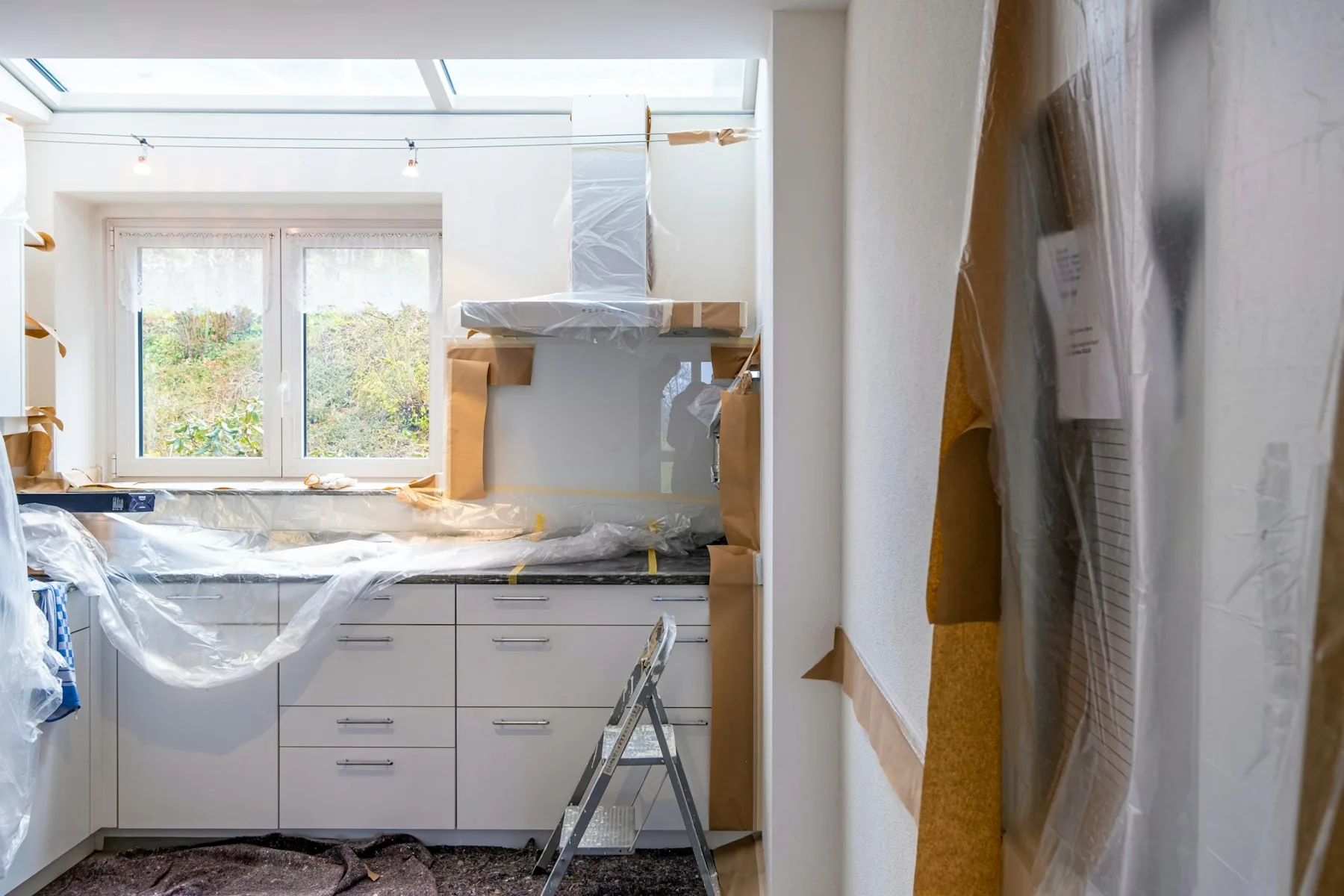 Kitchen mid-remodel with cabinets protected in plastic and paper